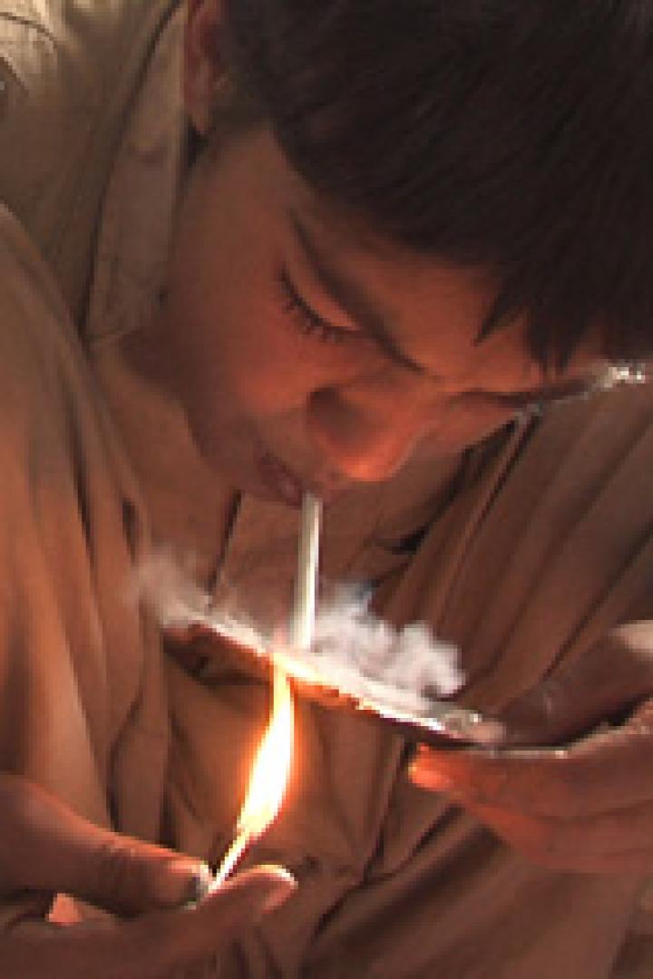 Ein Junge raucht eine Zigarette, während er ein Streichholz hält.