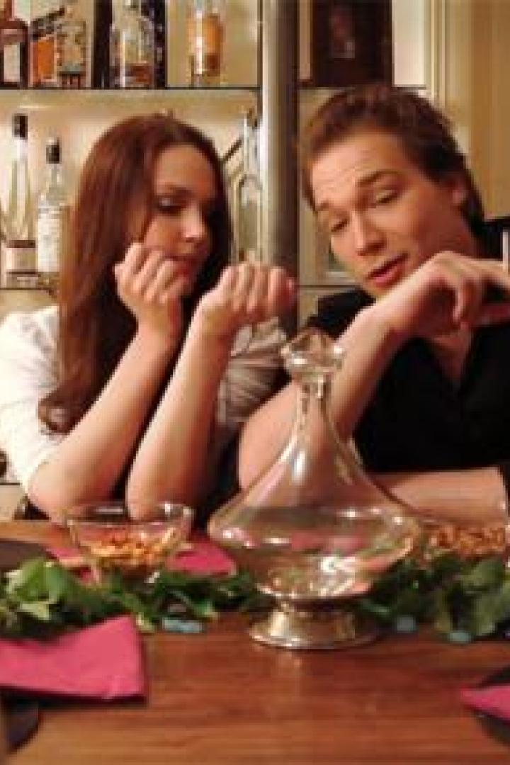 Ein Mann raucht am Tisch, während eine Frau neben ihm sitzt.