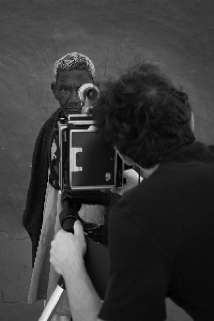 Ein Fotograf macht ein Porträt einer älteren Person mit einer Großformatkamera.