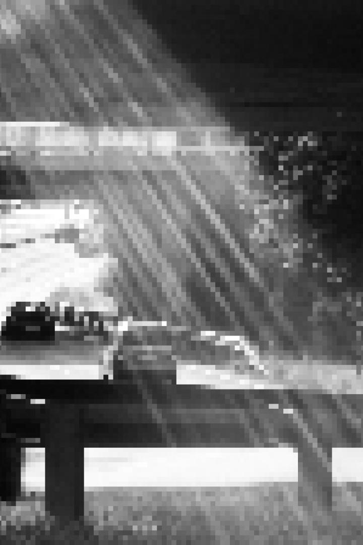 Sonnenstrahlen scheinen unter einer Autobahnbrücke auf eine Straße mit Autos.
