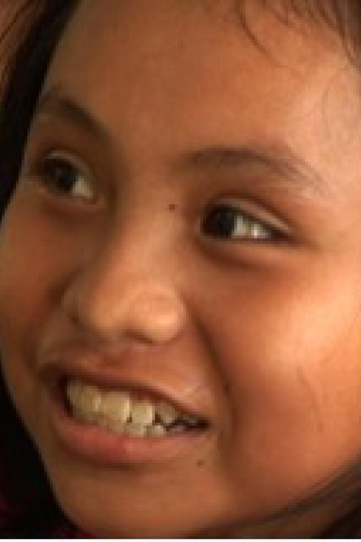 Ein junges Mädchen lächelt und schaut zur Seite.