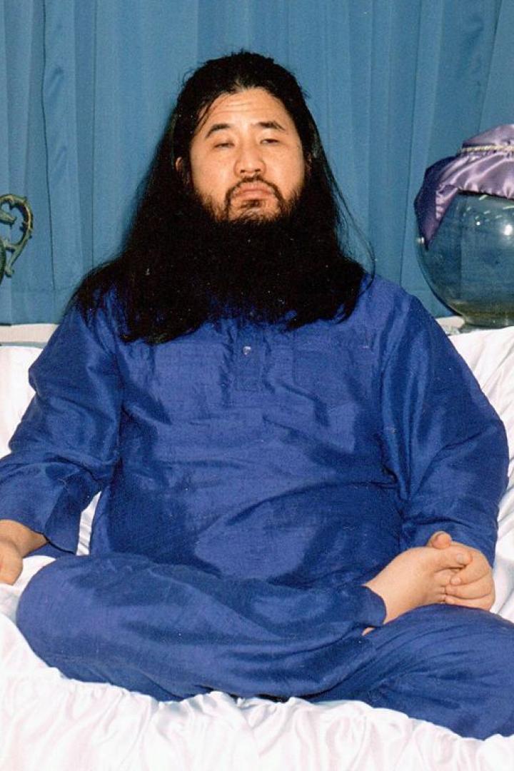 Ein Mann mit langem, dunklem Haar und Bart sitzt in Meditationshaltung.