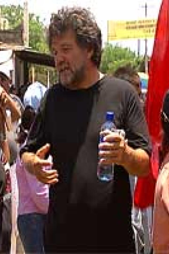 Eine Menschenmenge mit roten Fahnen demonstriert auf einer Straße.