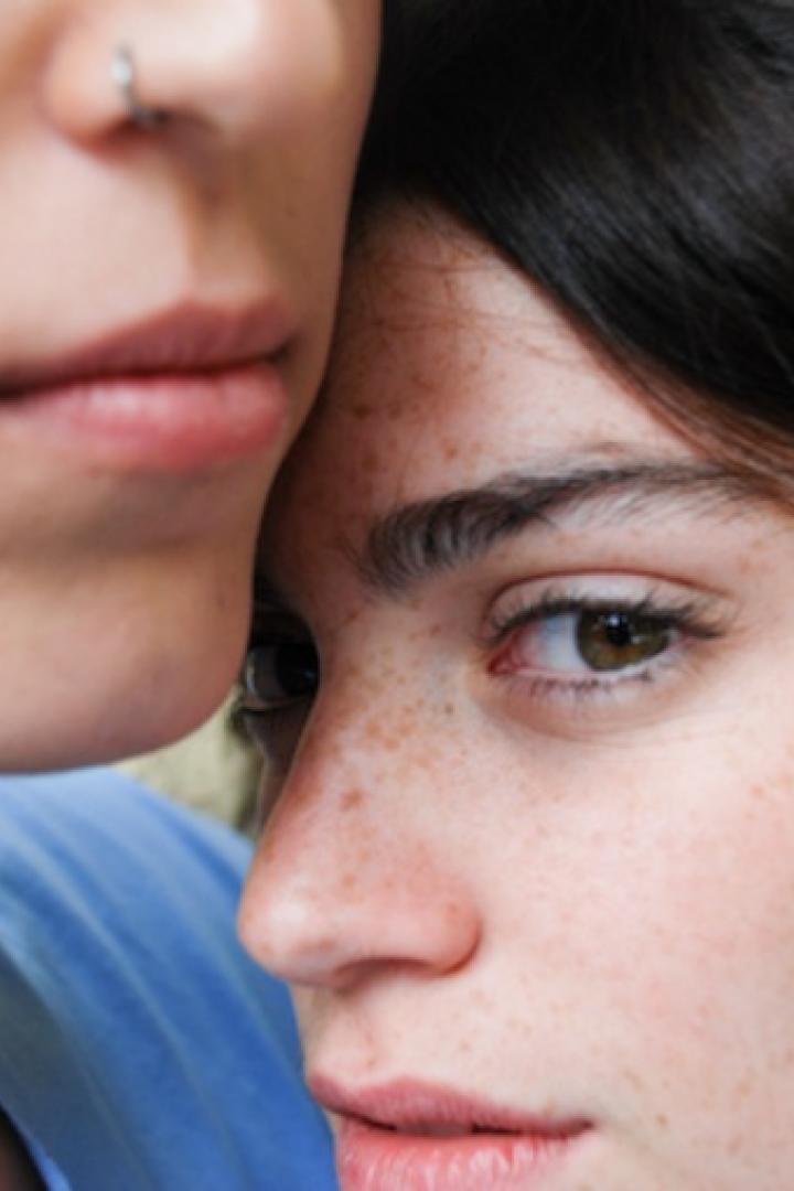 Zwei junge Frauen stehen eng beieinander.