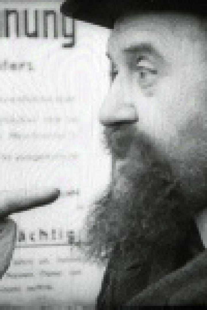 Ein Mann mit Bart zeigt auf ein Plakat mit der Aufschrift „Belohnung“.