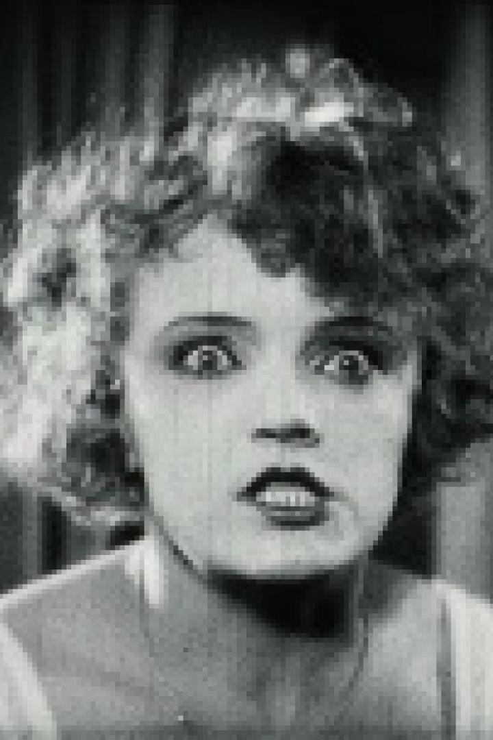 Eine Frau mit lockigem Haar blickt mit aufgerissenen Augen in die Kamera.