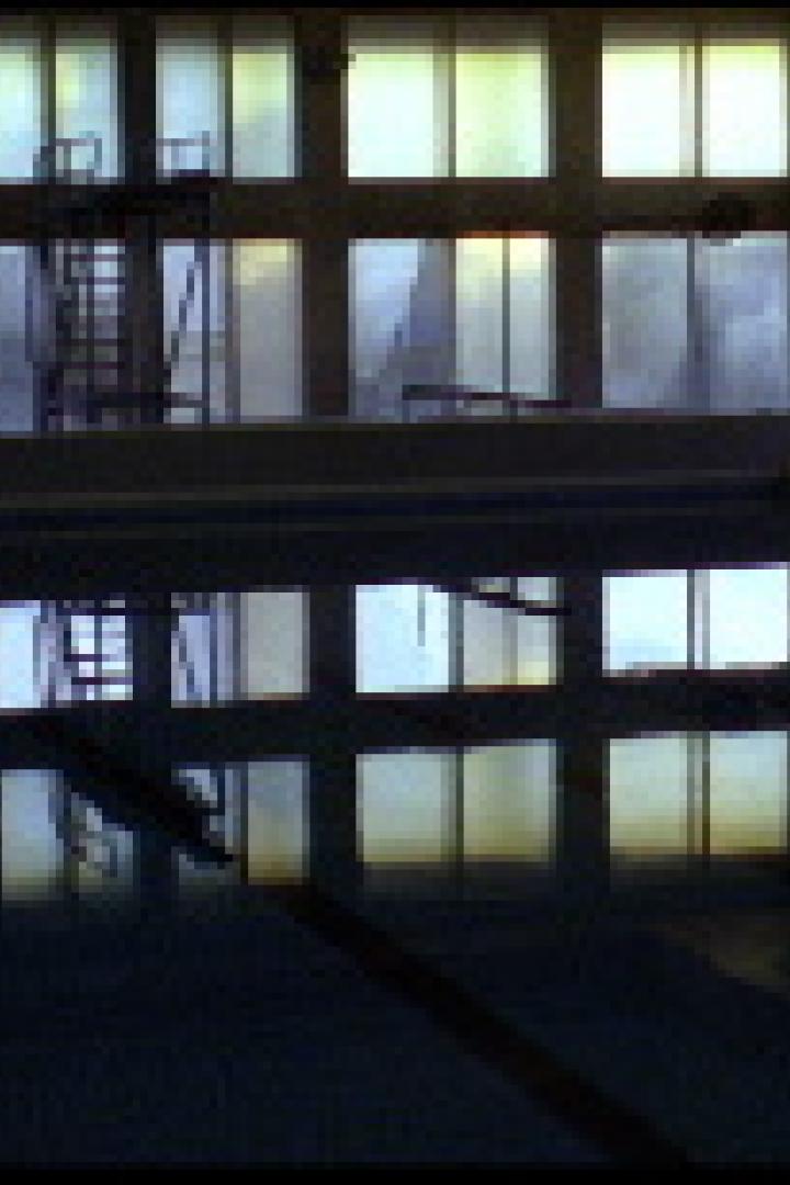Ein leeres Schwimmbecken mit Sprungturm spiegelt sich im Wasser.