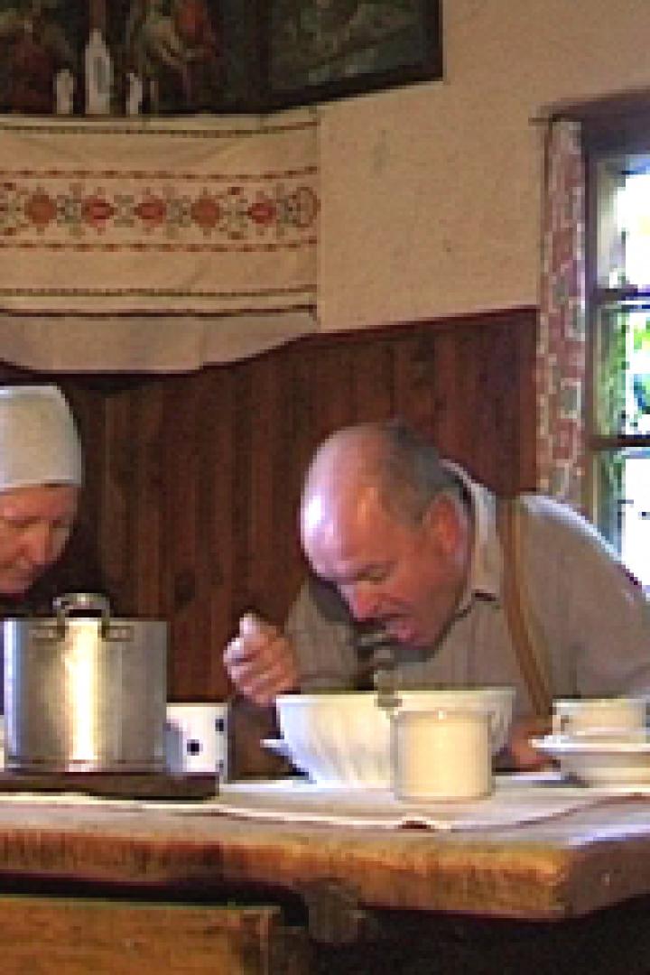 Eine Familie sitzt an einem Holztisch und isst gemeinsam eine Mahlzeit.
