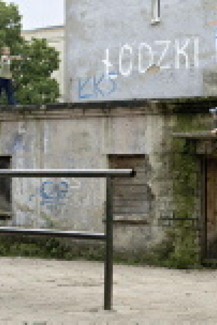 Zwei Personen üben Parkour an einer Mauer mit Graffiti.