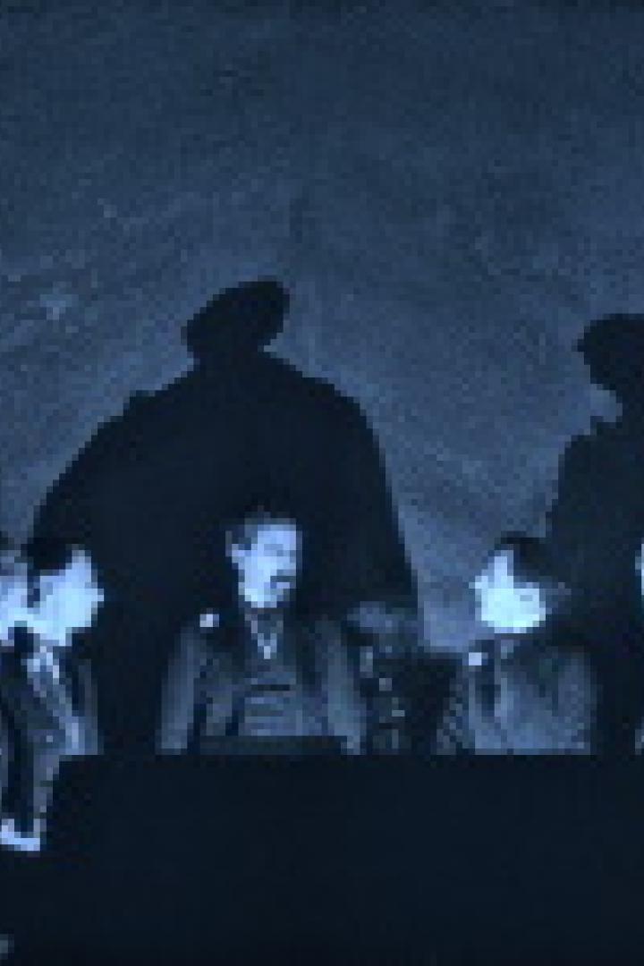 Eine Gruppe von Personen sitzt an einem Tisch, während Schatten an die Wand geworfen werden.