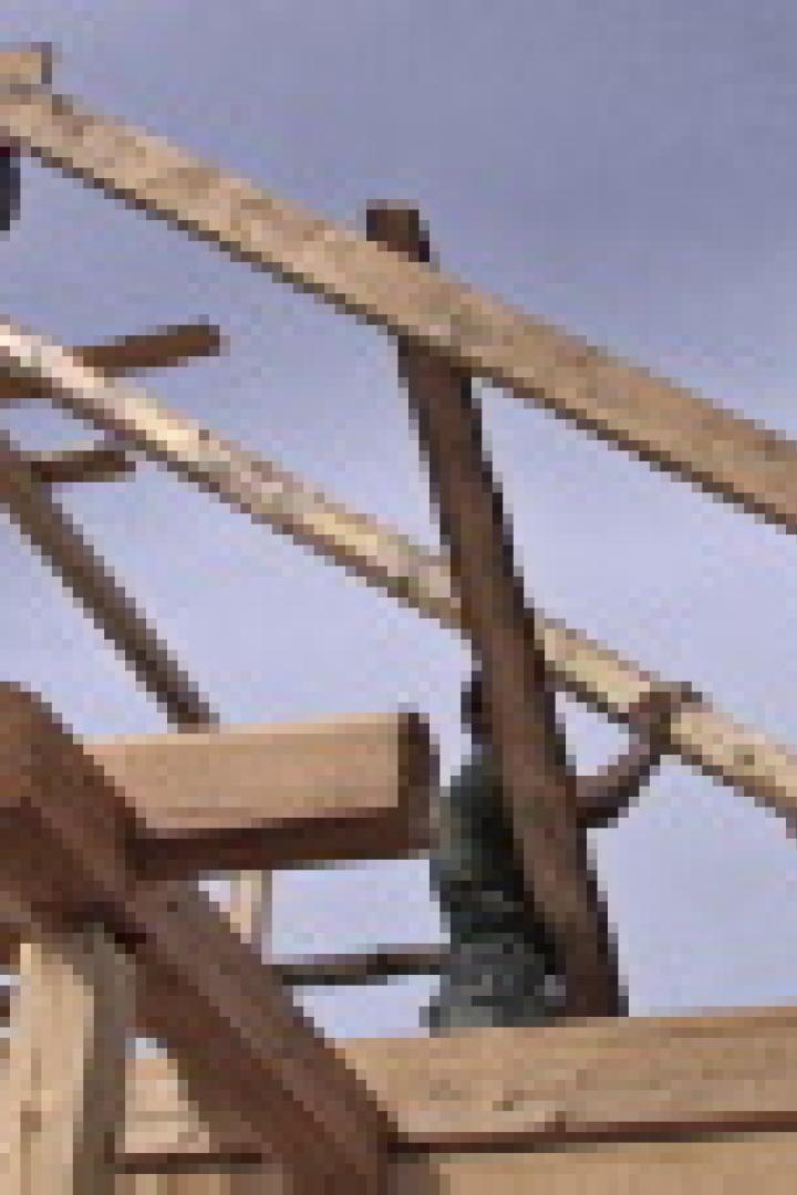 Mehrere Zimmerleute errichten ein Holzgebäude.