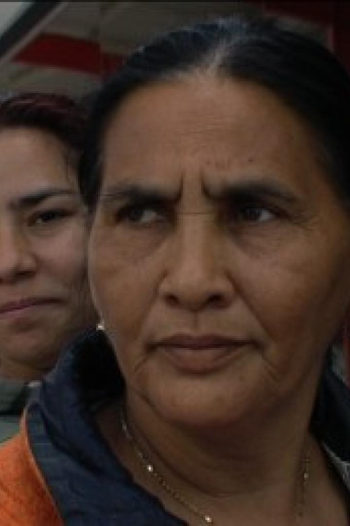 Eine ältere Frau mit zwei jüngeren Frauen im Hintergrund.