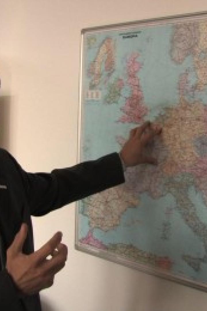 Ein Mann im Anzug zeigt auf eine Europakarte an der Wand.
