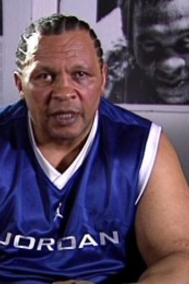 Ein Mann mit geflochtenem Haar trägt ein blaues Jordan-Trikot.