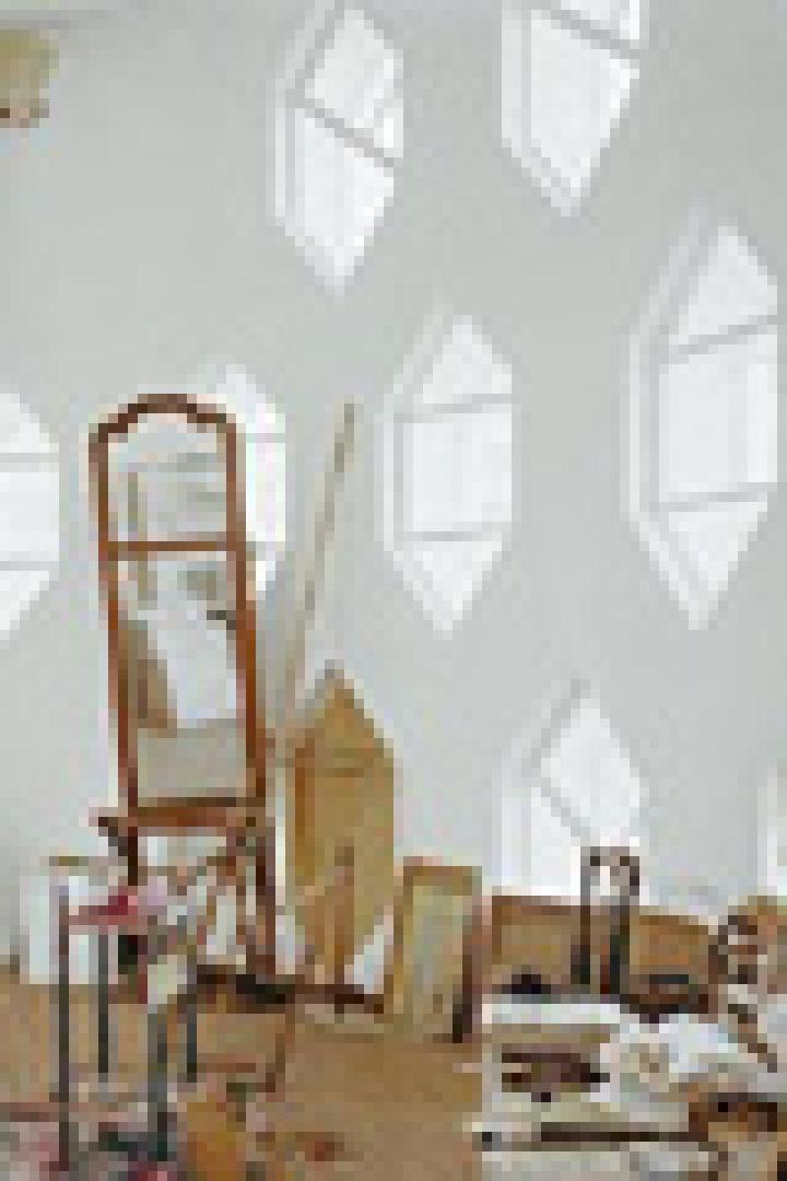 Ein Atelier mit vielen sechseckigen Fenstern, einer Leiter und diversen Kunstgegenständen.