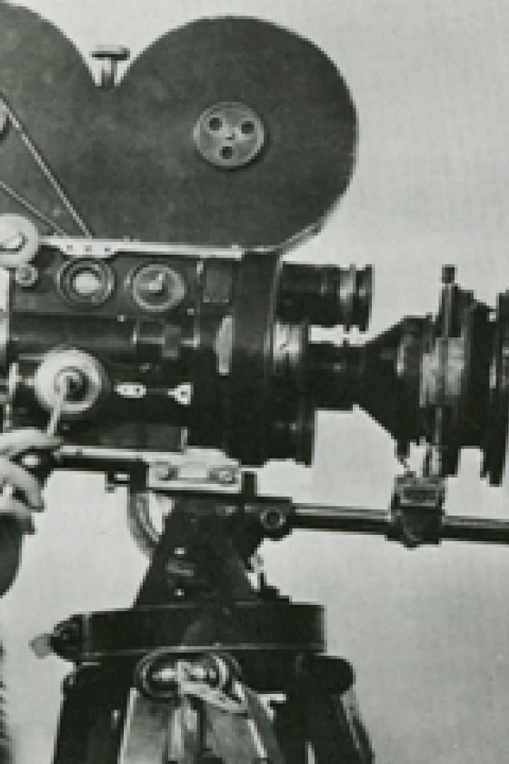 Eine Frau und ein Mann stehen neben einer alten Filmkamera.