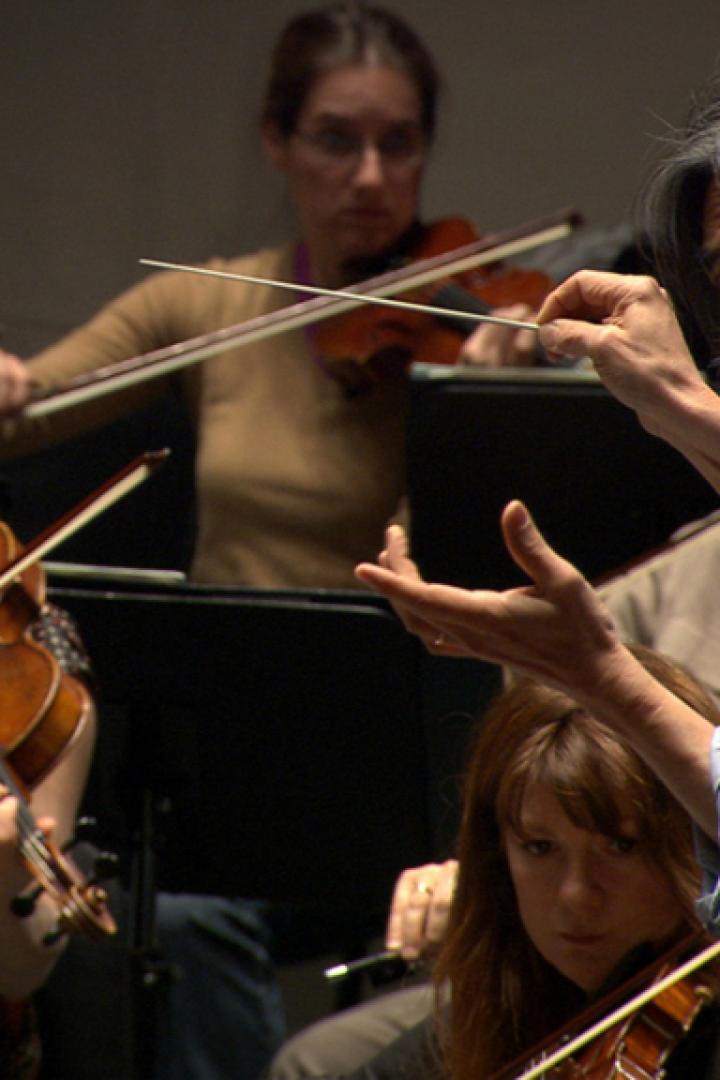 Ein Dirigent leitet ein Orchester mit Geigern.