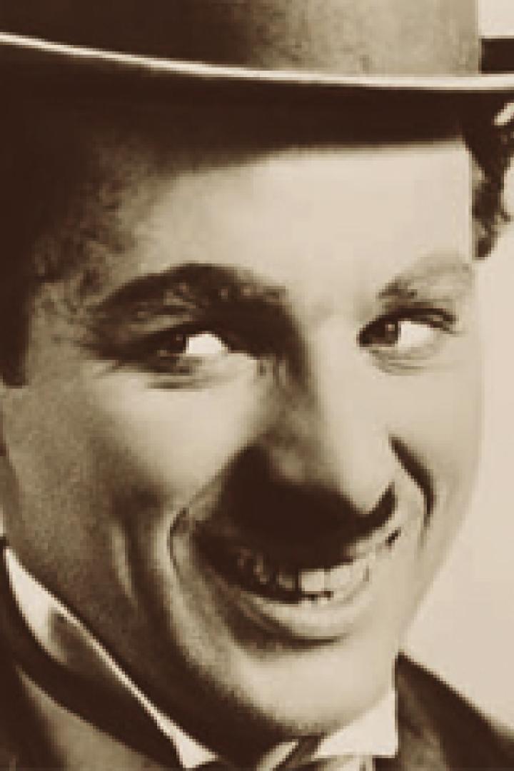Ein Porträt von Charlie Chaplin mit Melone und einem verschmitzten Lächeln.