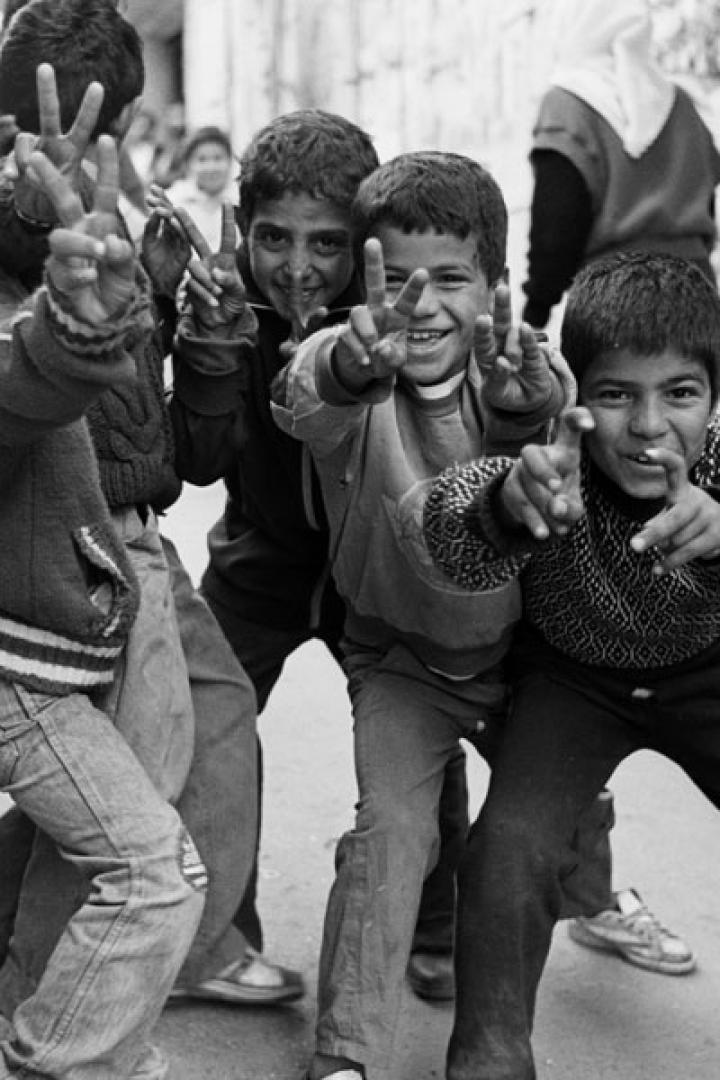 Eine Gruppe von Jungen posiert und zeigt Friedenszeichen in einer Gasse.