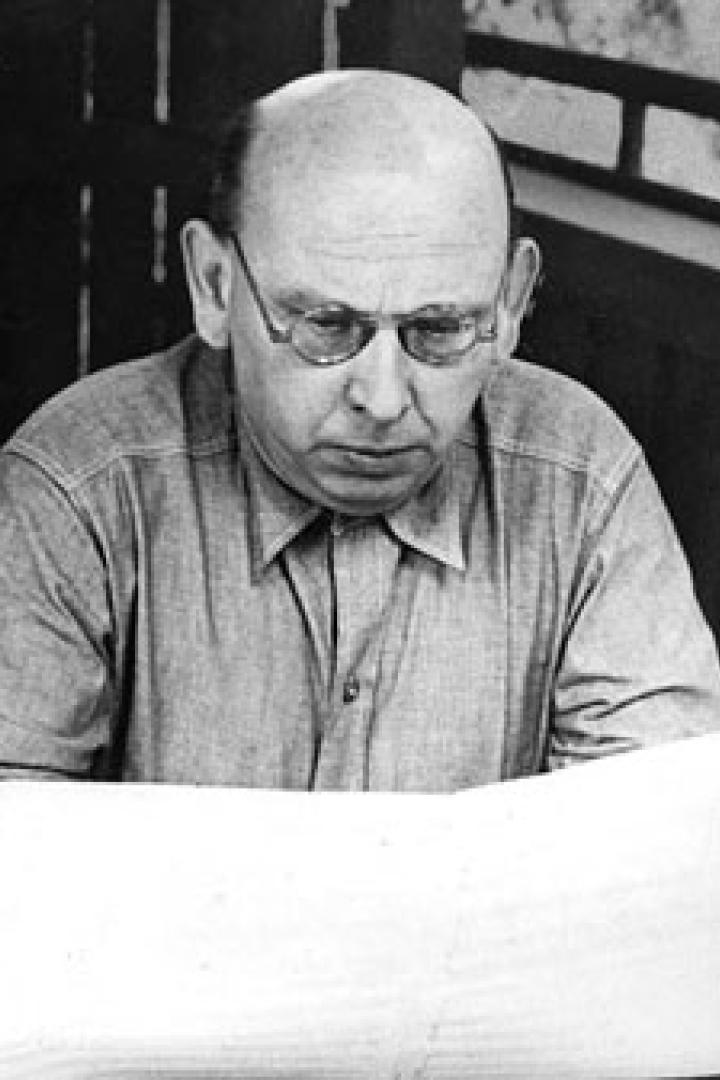Ein Mann mit Brille liest ein großes Blatt Papier.