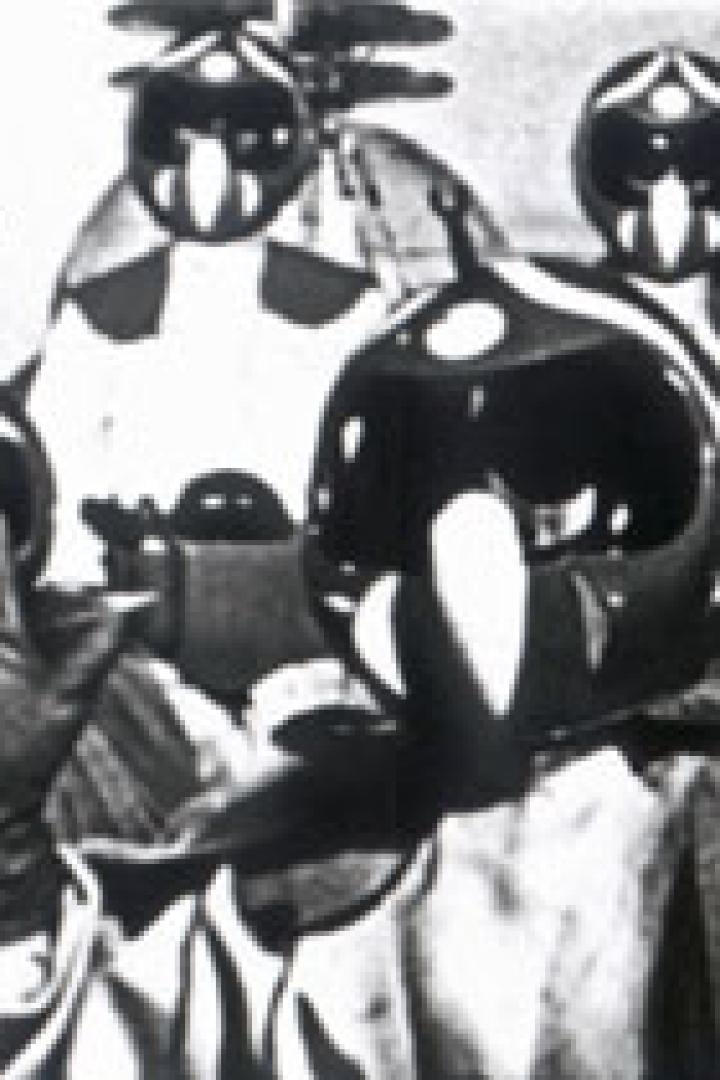 Eine Gruppe von Personen trägt futuristische Helme und Umhänge.