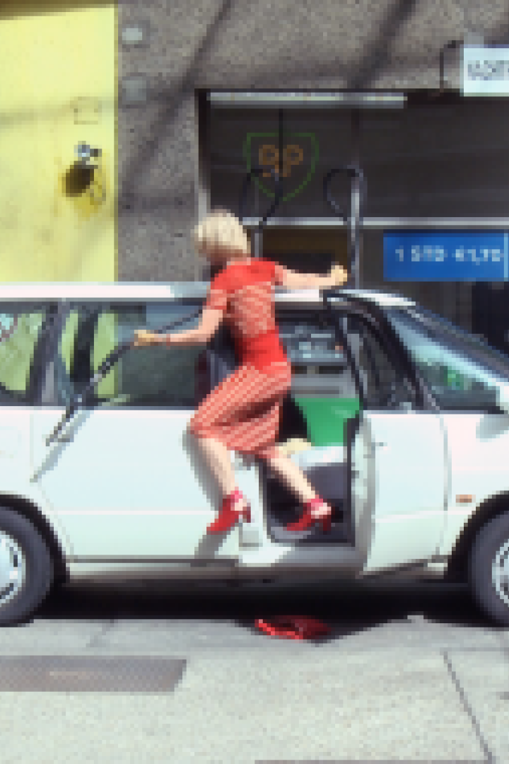 Eine Frau steigt in einem roten Kleid in einen weißen Van an einer BP-Tankstelle.