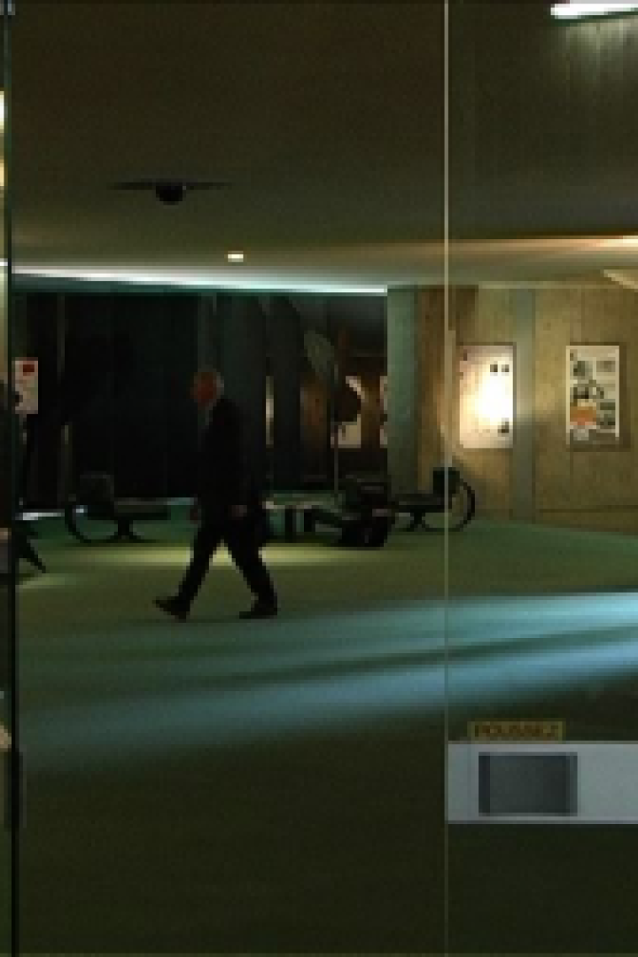 Ein Mann geht durch eine Drehtür, während andere Personen in einer Lobby zu sehen sind.