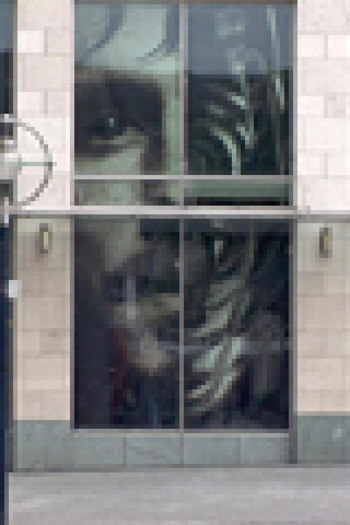 Ein Gebäude mit großen Fenstern, auf denen ein Nike-Werbeplakat mit dem Gesicht eines Sportlers zu sehen ist.