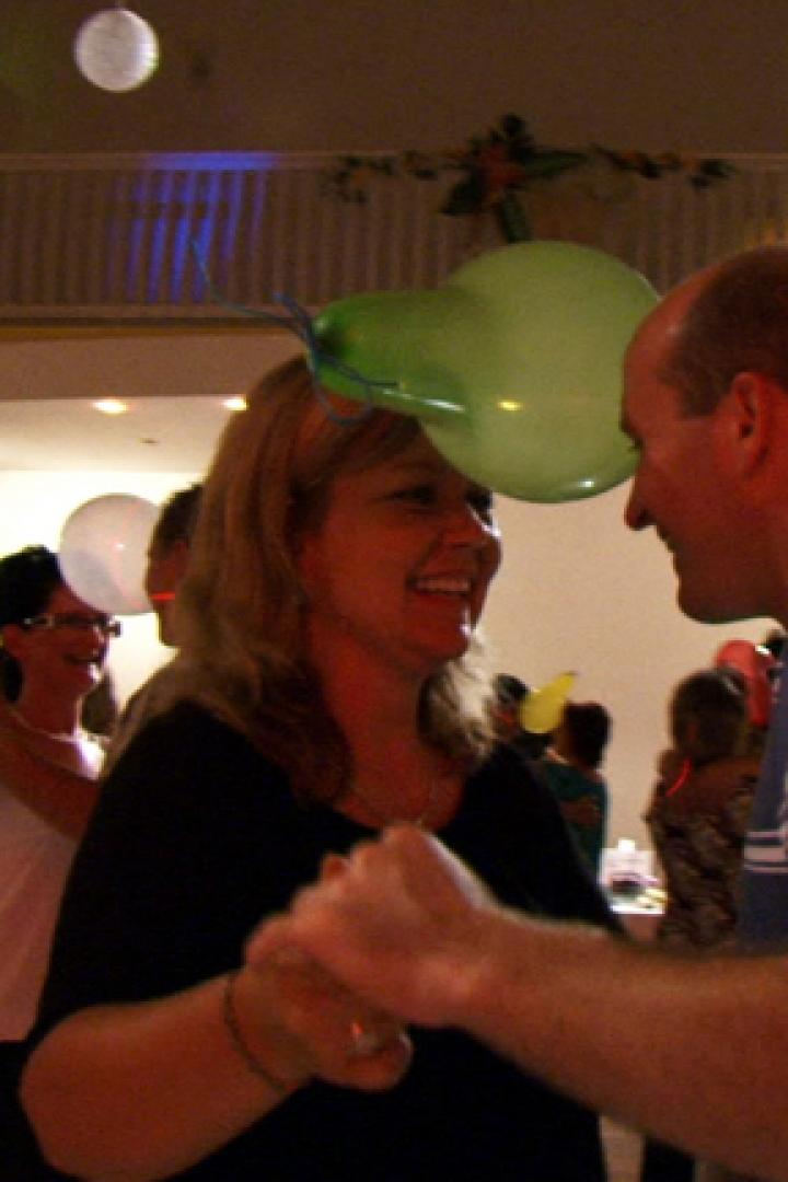 Ein Paar tanzt mit einem Ballon zwischen ihren Köpfen auf einer Party.