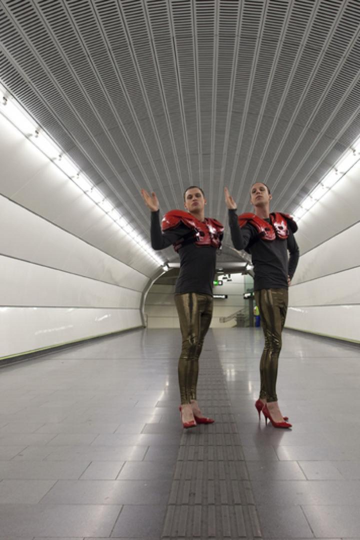 Zwei Personen in ungewöhnlicher Kleidung stehen in einer U-Bahn-Station.