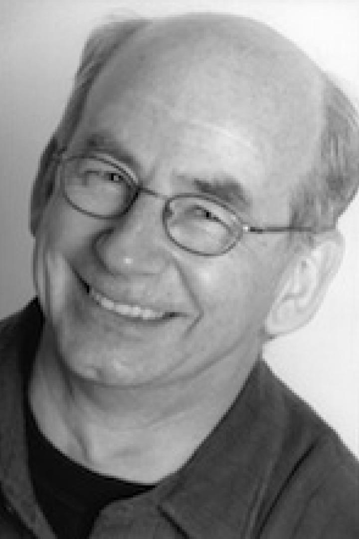 Ein lächelnder Mann mit Brille in Schwarzweiß.