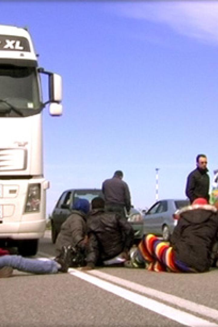 Eine Gruppe von Menschen blockiert eine Straße mit einem LKW.