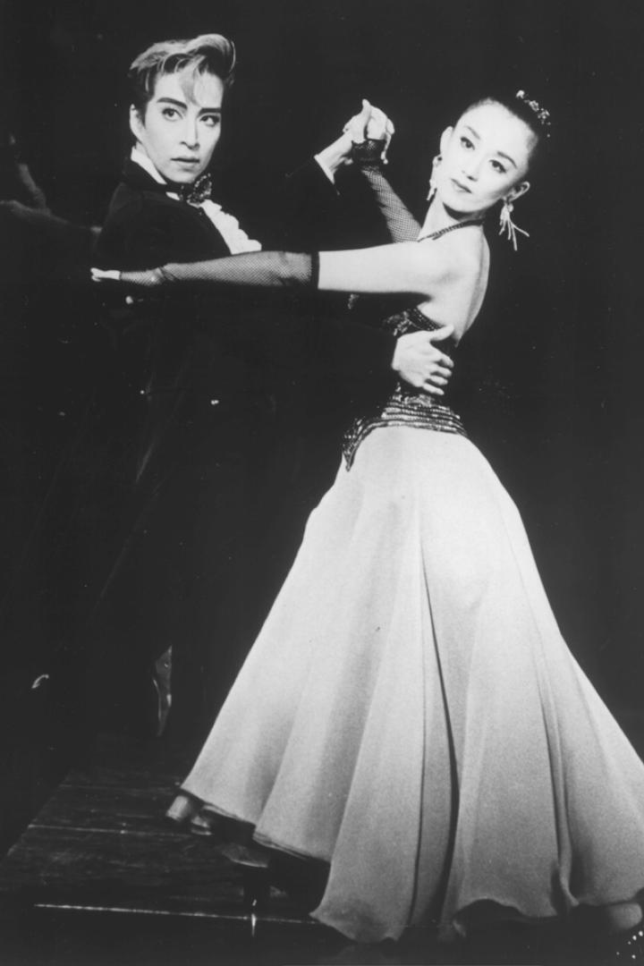 Ein Paar tanzt in eleganten Kostümen auf einer Bühne.