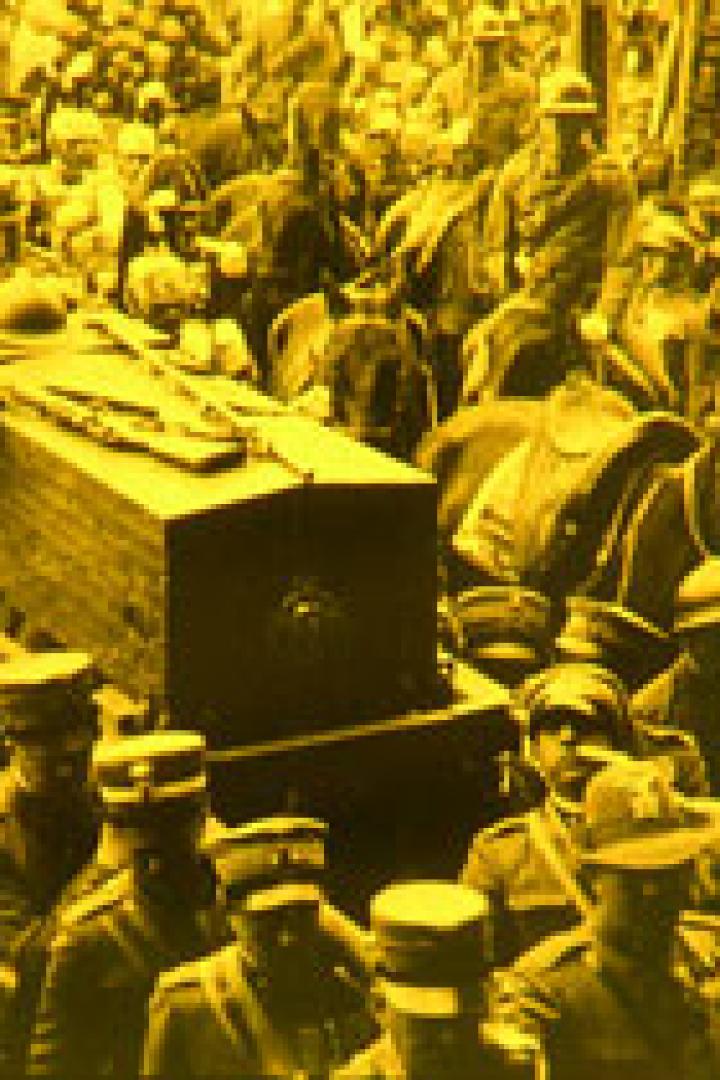 Eine Menschenmenge begleitet einen Sarg, der von Soldaten getragen wird.