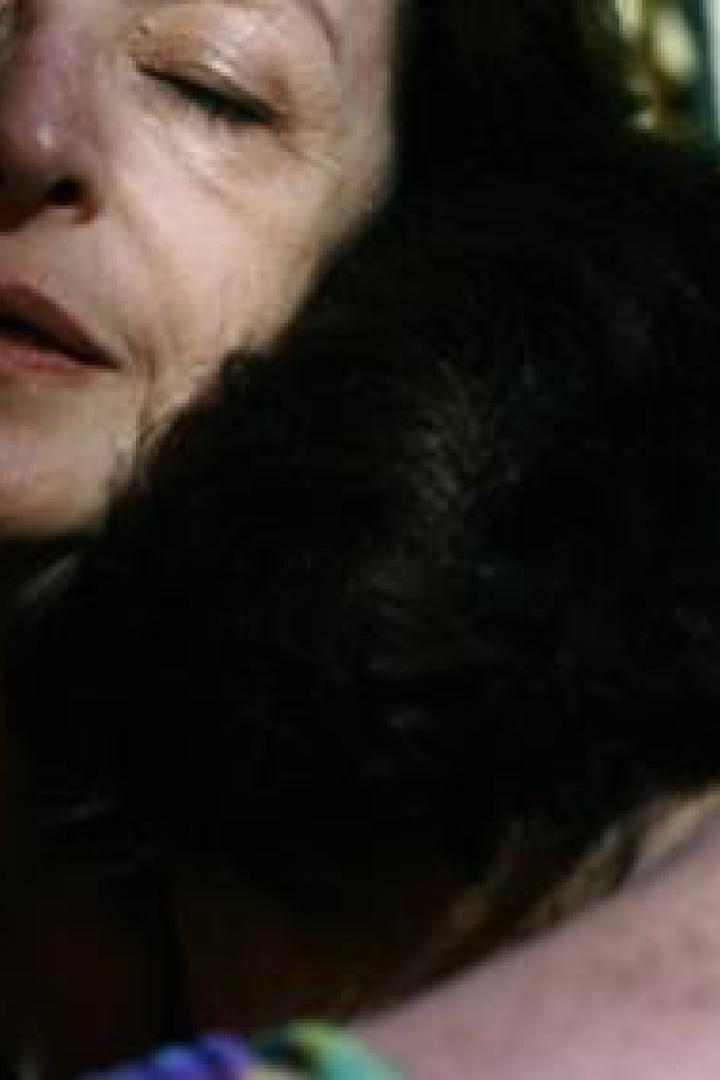 Eine ältere Frau umarmt ein Kind mit dunklen Haaren.