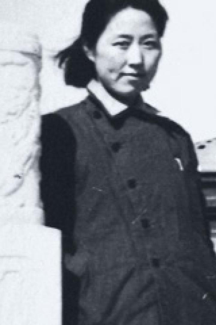 Eine junge Frau steht neben einer verzierten Steinsäule.