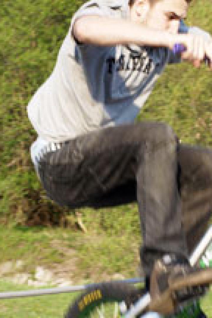 Ein junger Mann führt einen Trick mit seinem Trial-Bike im Freien aus.