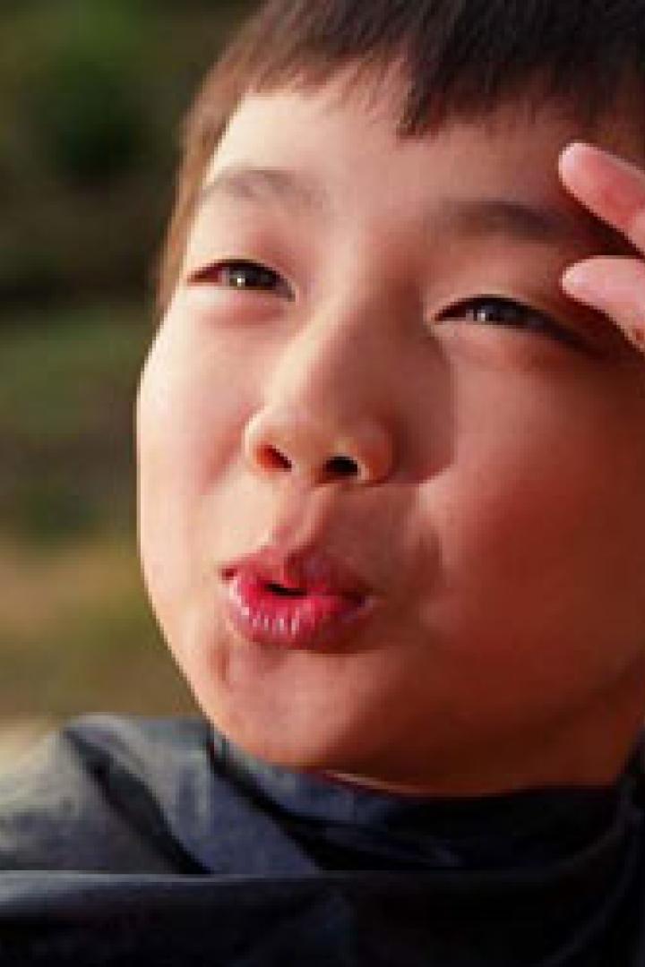 Ein Junge formt mit seinen Fingern eine kleine Geste vor seiner Stirn.