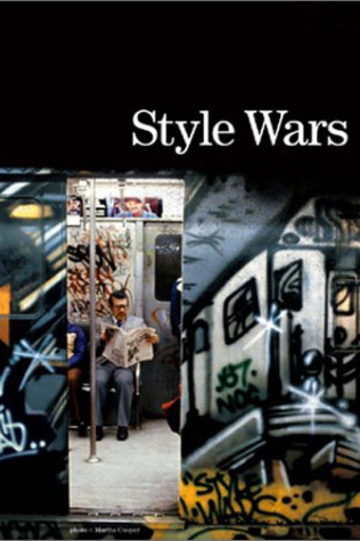 Ein Mann liest Zeitung in einer U-Bahn, deren Waggons mit Graffiti besprüht sind.