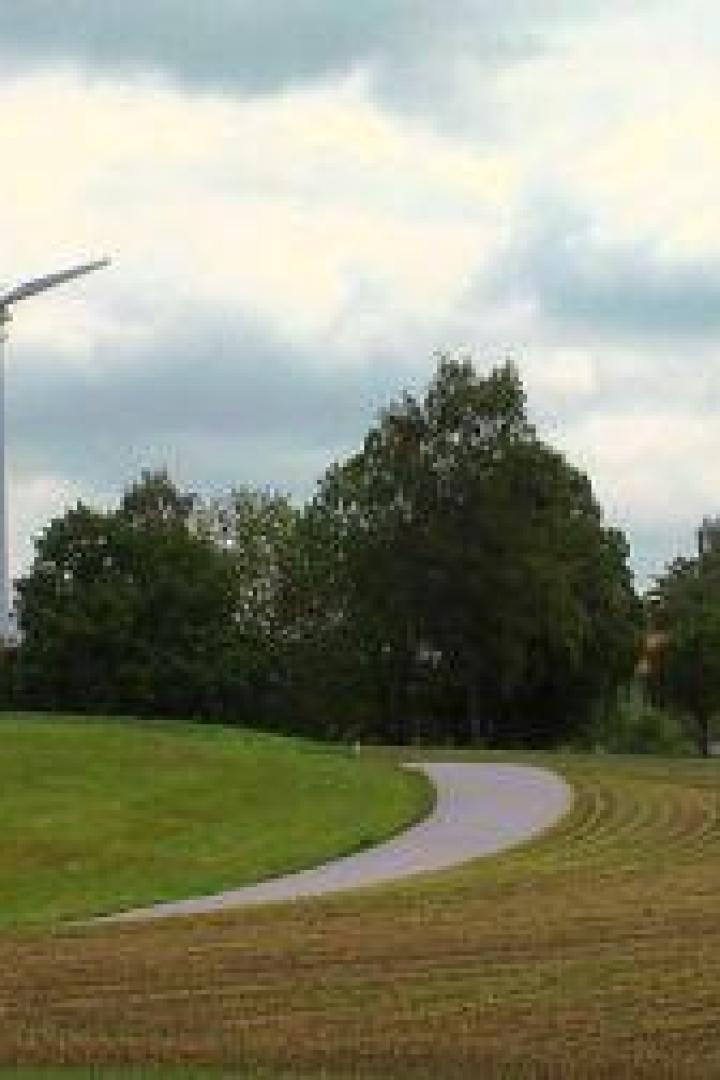 Zwei Windräder stehen auf einem Feldweg in ländlicher Umgebung.