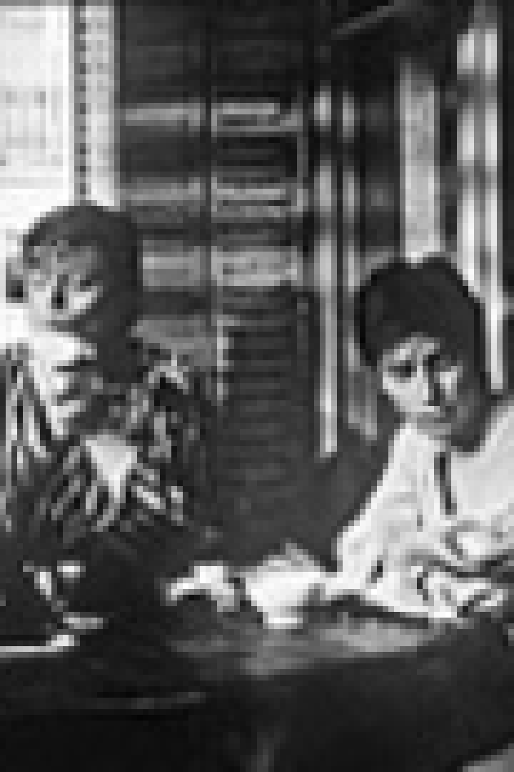 Zwei Frauen sitzen an einem Tisch in einem Raum mit starkem Schattenwurf.