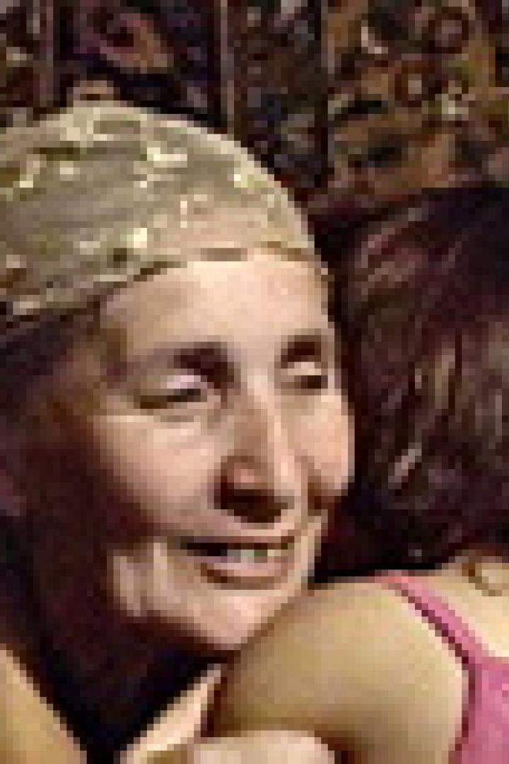 Eine ältere Frau mit Kopftuch umarmt ein junges Mädchen.