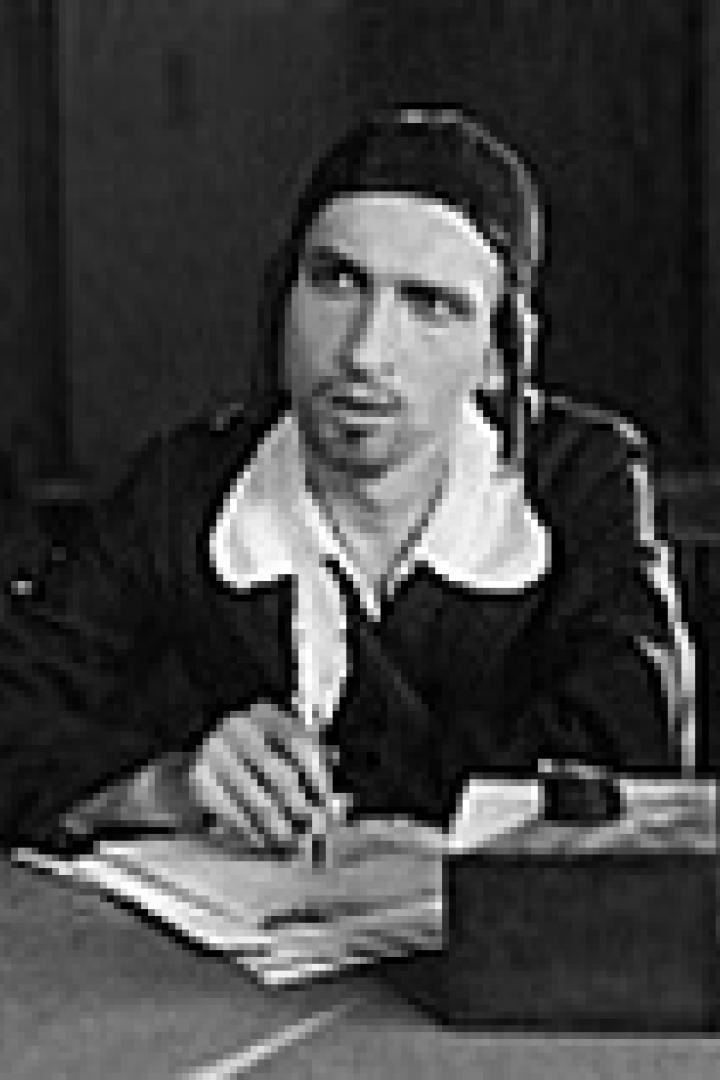 Ein Mann mit Mütze sitzt an einem Schreibtisch mit Feder und Tinte.