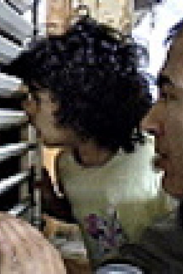 Ein Mann und ein Kind schauen durch eine Jalousie.