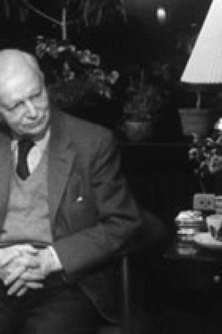 Ein älterer Mann sitzt in einem Sessel und spricht mit einer Person, die ihm gegenübersitzt.