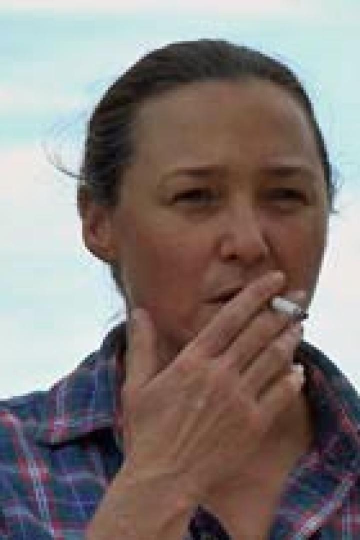 Eine Frau mit kariertem Hemd raucht eine Zigarette.