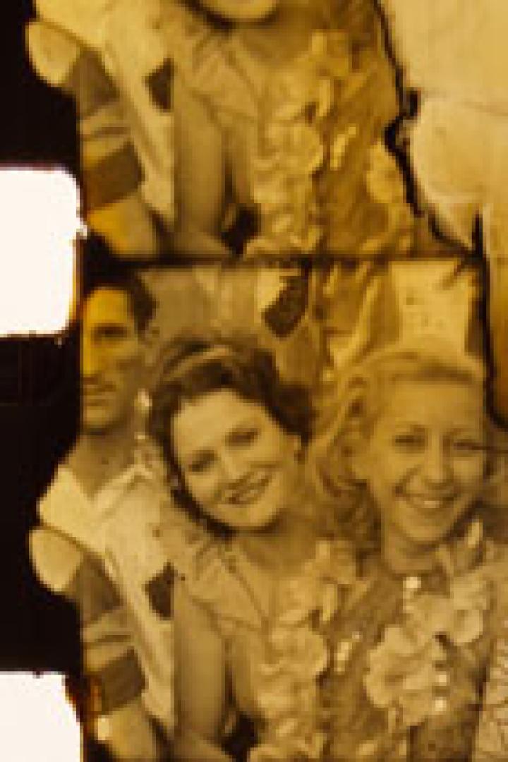 Beschädigtes Foto zeigt eine Gruppe lächelnder Menschen, möglicherweise aus den 1940er Jahren.