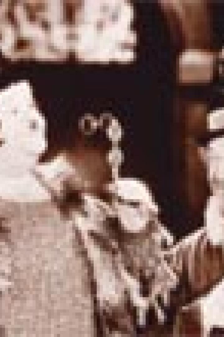 Stan Laurel und Oliver Hardy, als verkleidete Frauen, stehen nebeneinander.