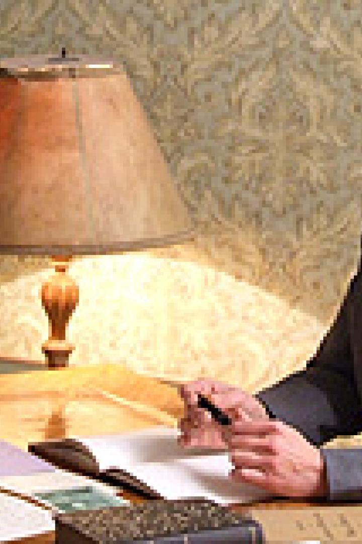 Eine Frau sitzt an einem Schreibtisch und schreibt in ein Buch.