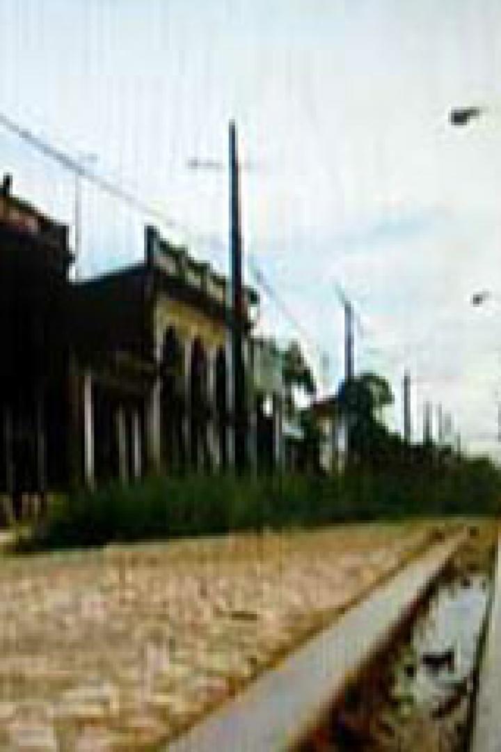 Eine Straße mit alten Gebäuden und Bahngleisen in einer ländlichen Gegend.